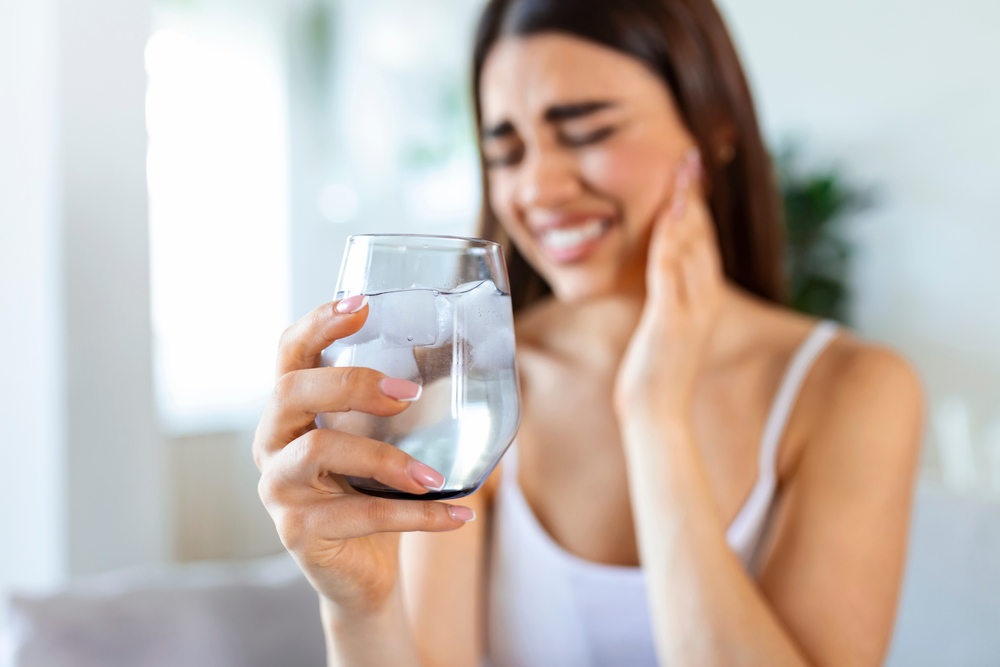 Young,Woman,With,Sensitive,Teeth,And,Hand,Holding,Glass,Of
