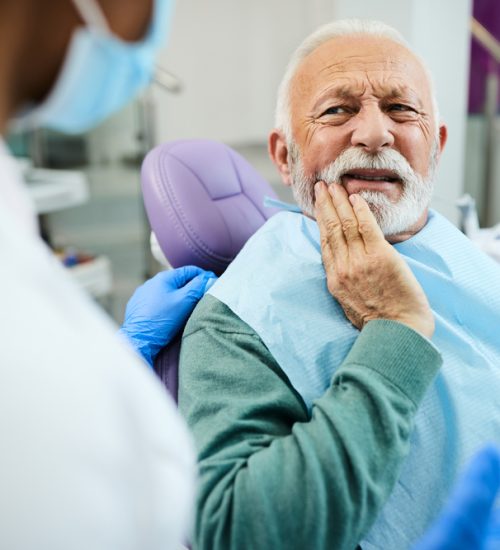 Mature,Man,Talking,About,Toothache,Problems,With,His,Dentist,At